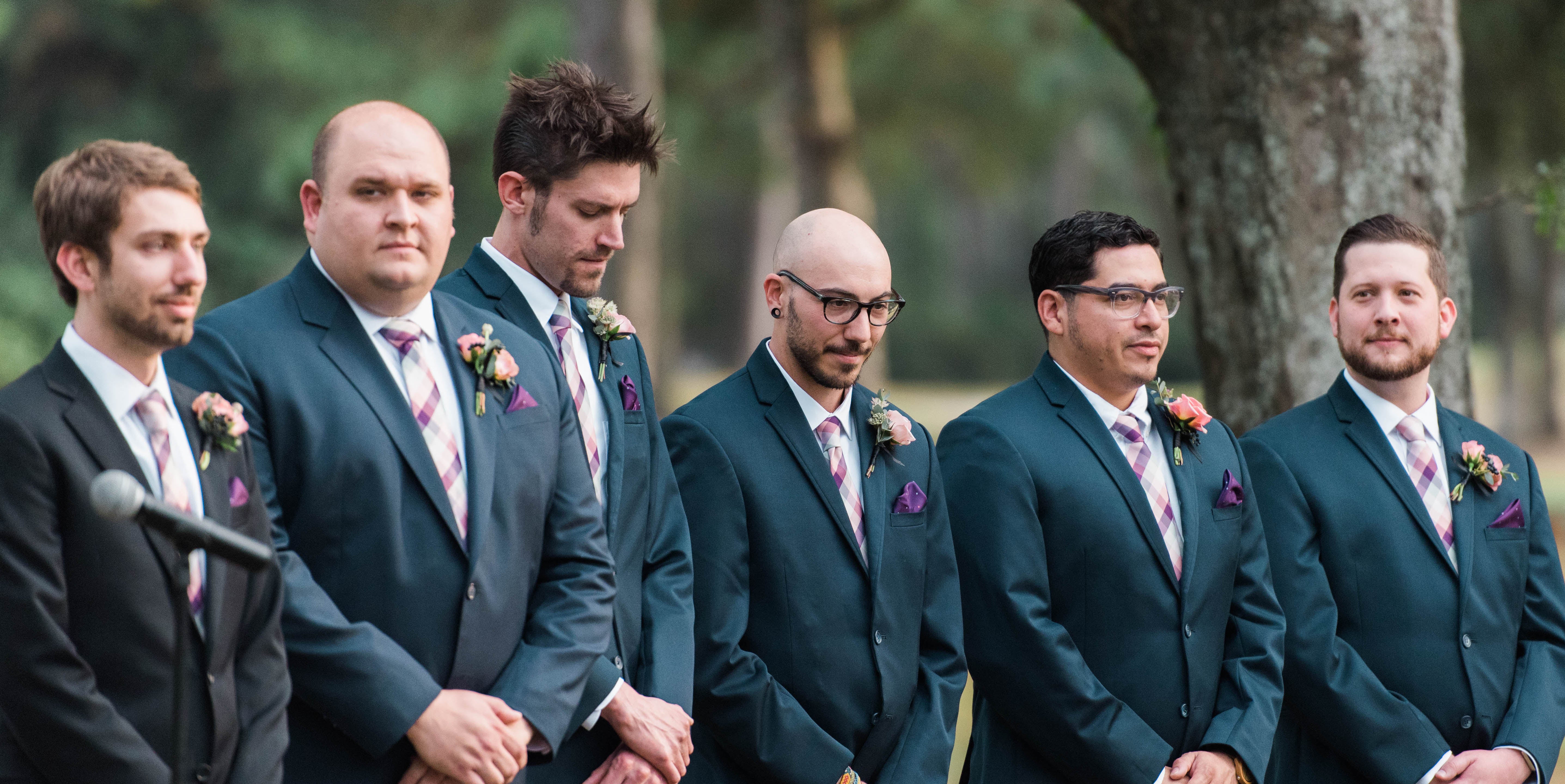 Groomsmen standing in a line during an outdoor wedding ceremony