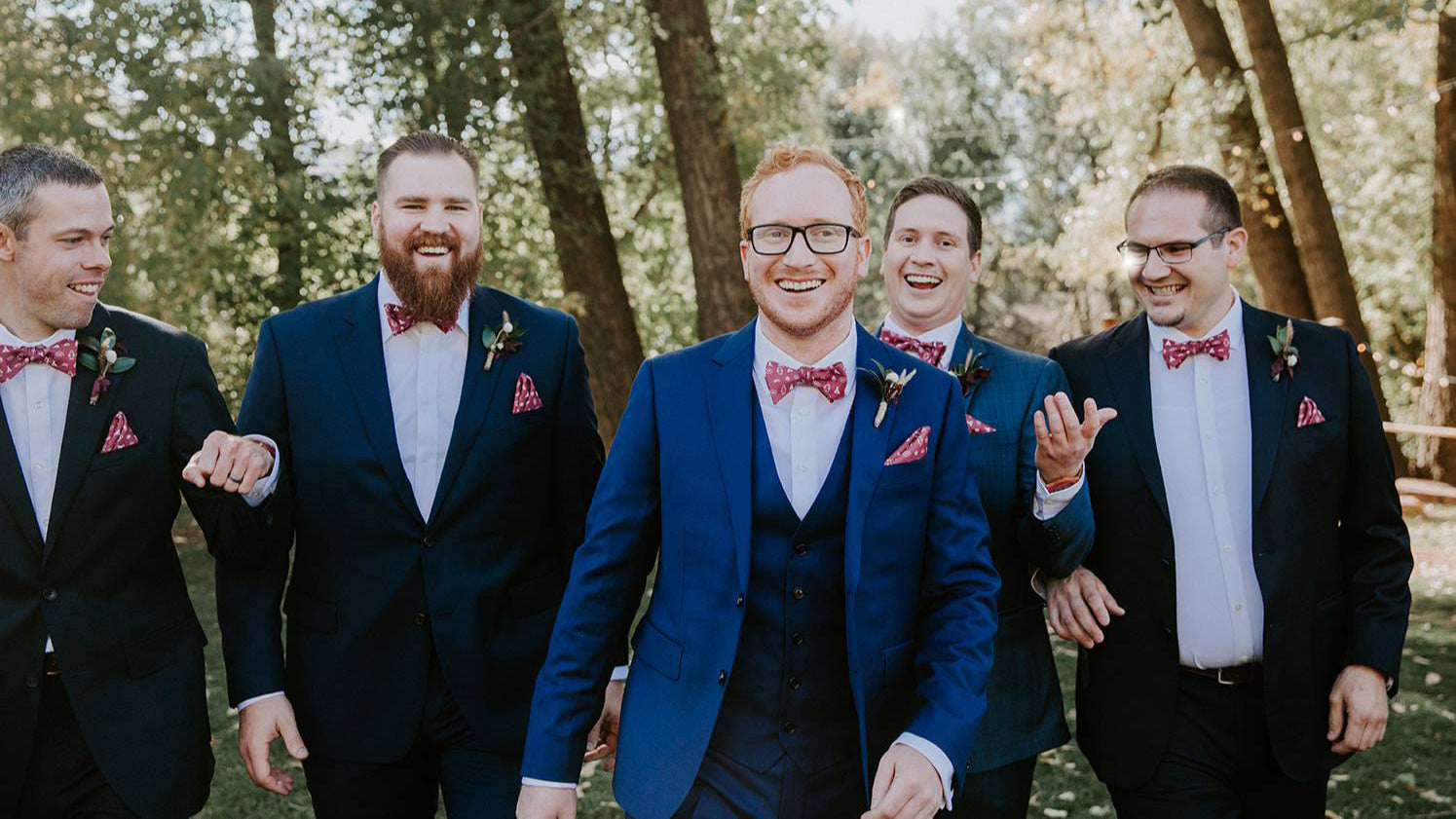 groom and groomsmen wearing blue suits and red bow ties