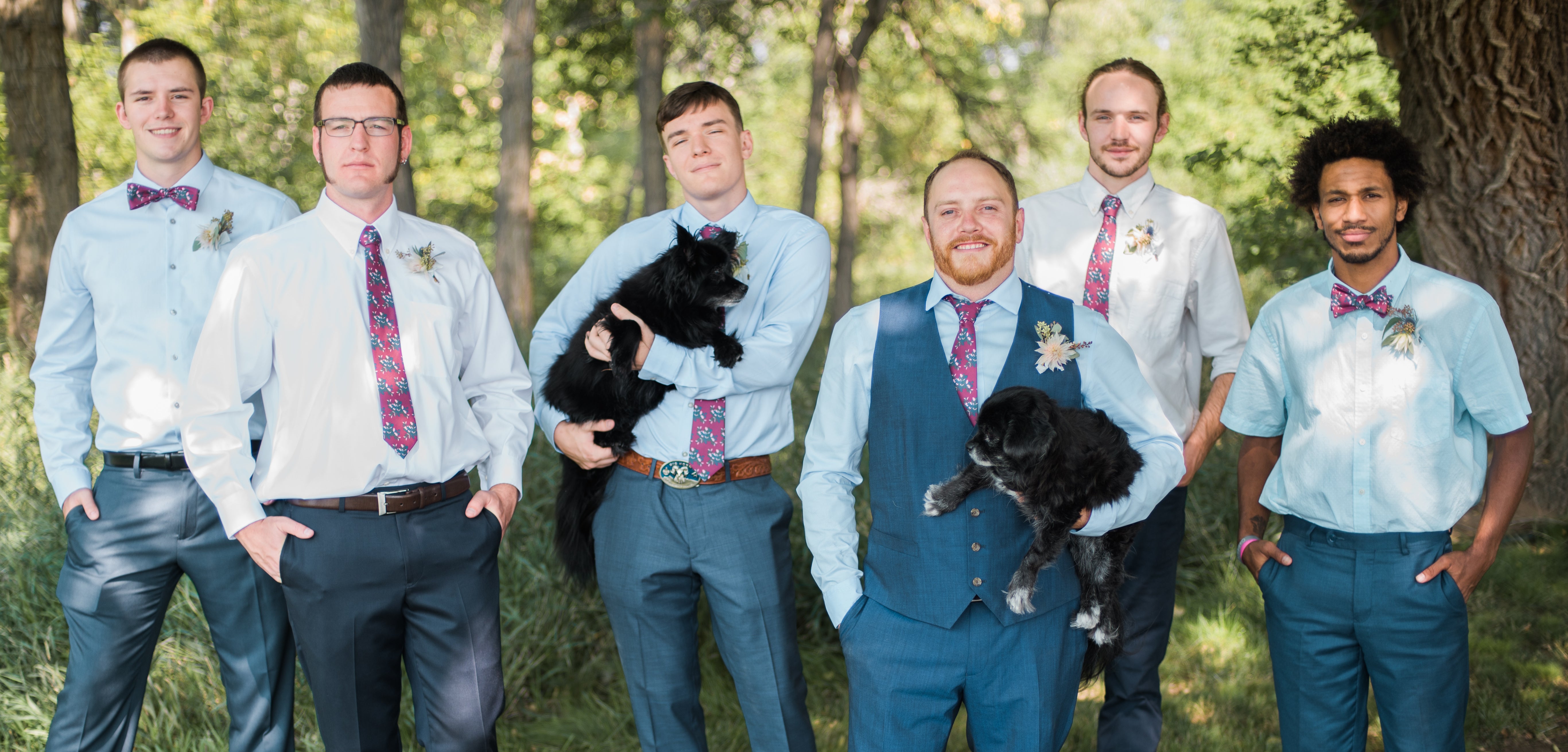 Groomsmen and groom wearing floral ties and bow ties holding dogs