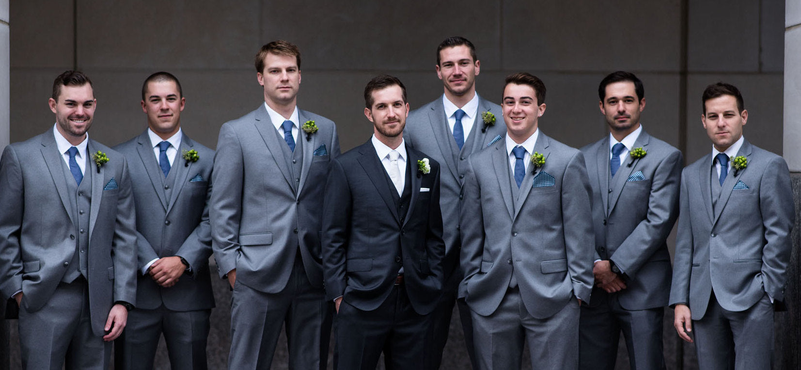 Group of men posing for wedding photos in suits and ties