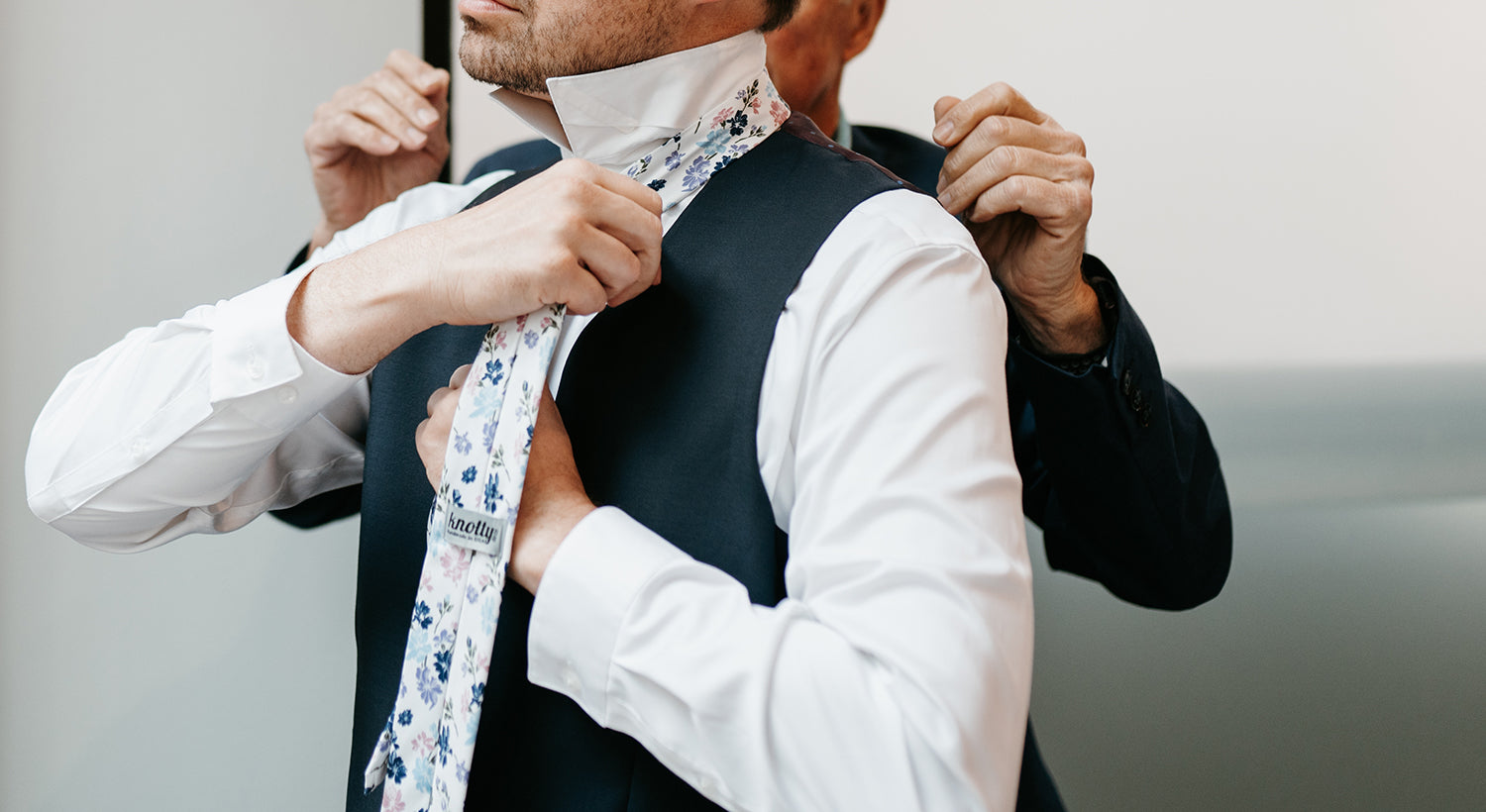 Groom tying necktie on wedding day