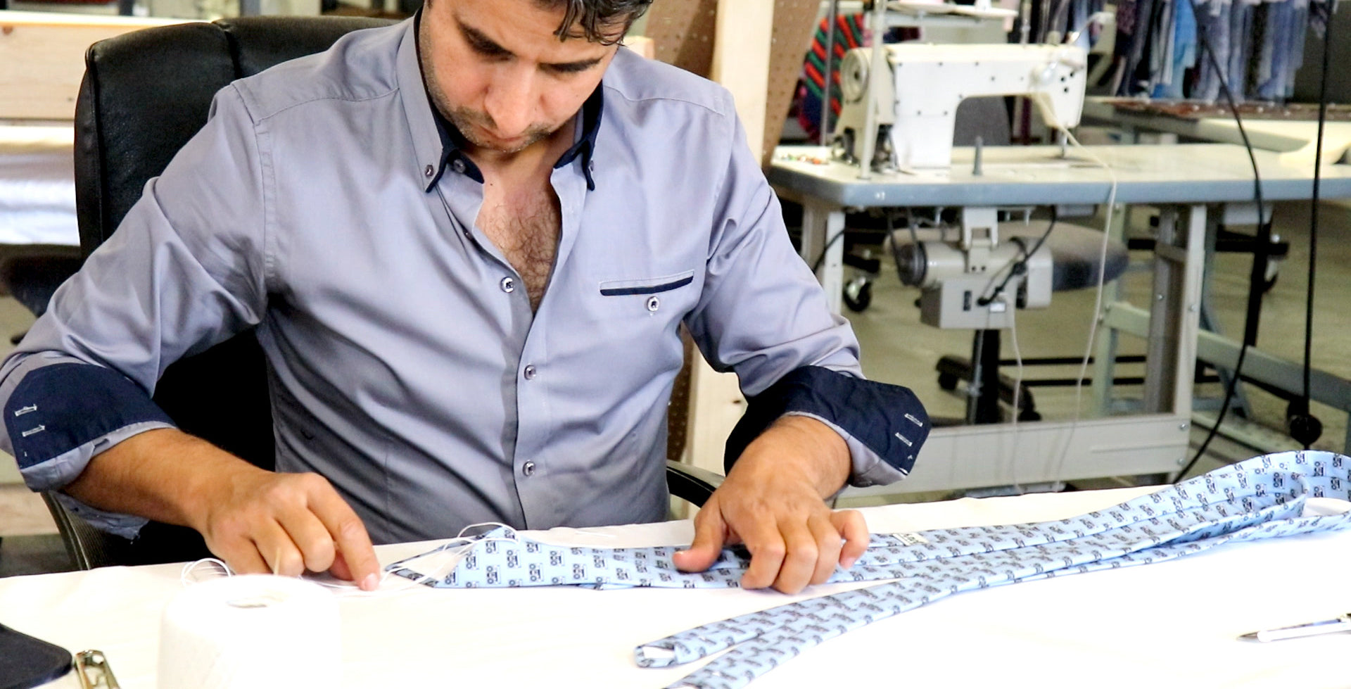 Man sewing necktie finishing stitch in manufacturing facility