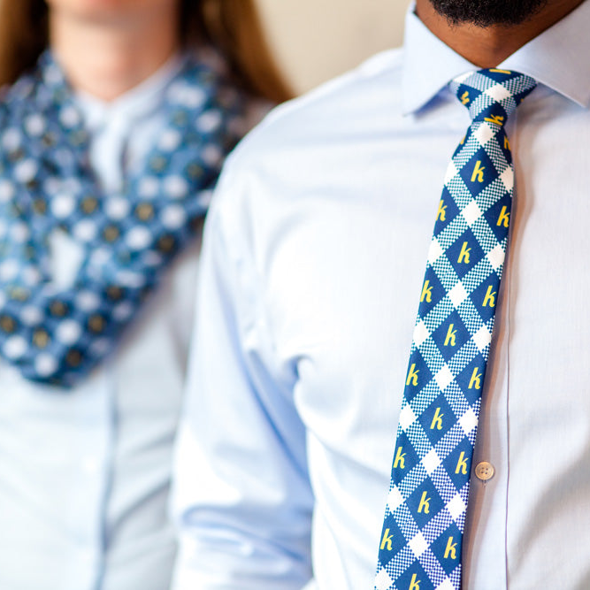 Close-up of a person wearing a blue custom tie with yellow pattern.