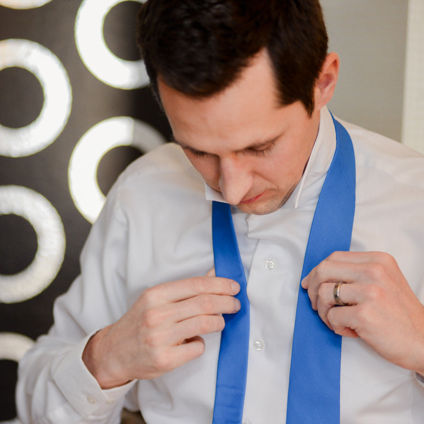 Man tying blue necktie