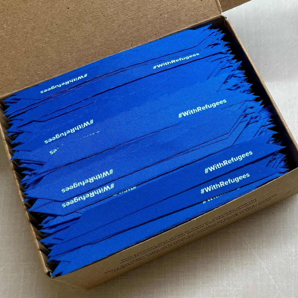 box containing thousands of #withrefugees ribbons