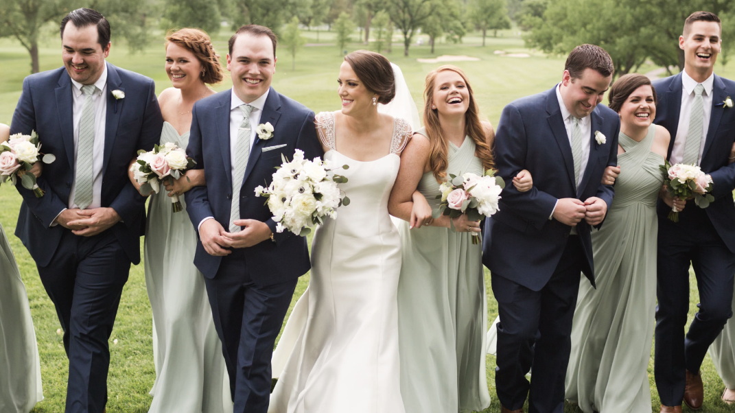 Wedding party walking together outdoors with floral bouquets