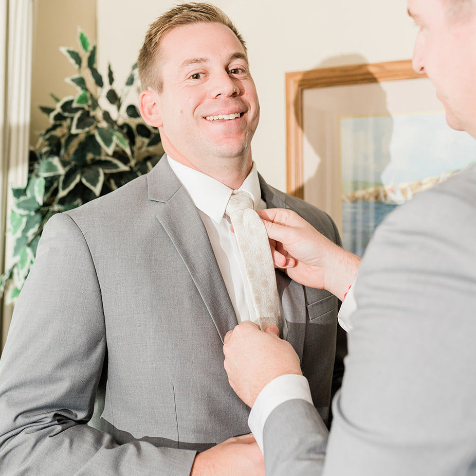man smiling as his father helps him put on a necktie