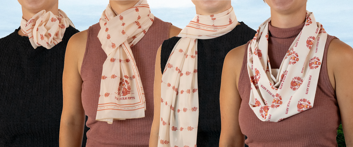 Four different styles of a cream scarf with red floral patterns and text, shown against a soft blue sky background.