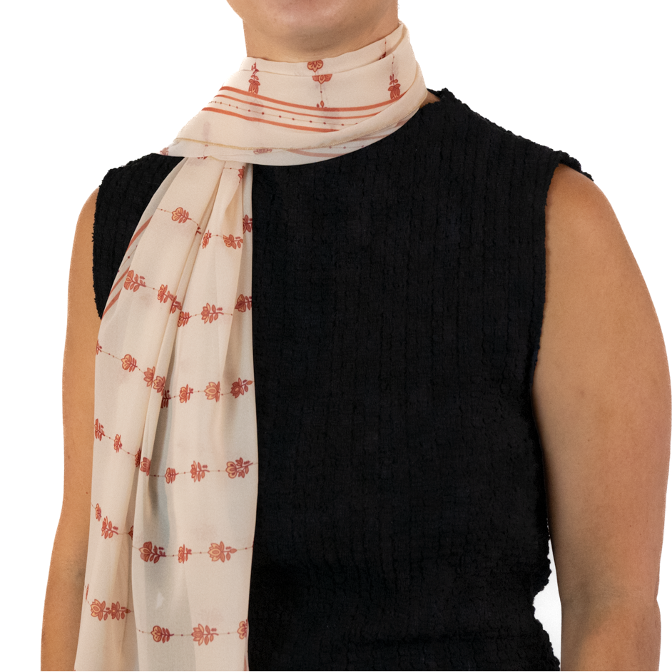 A woman wearing a cream-colored rectangle scarf with a rust-red floral pattern.