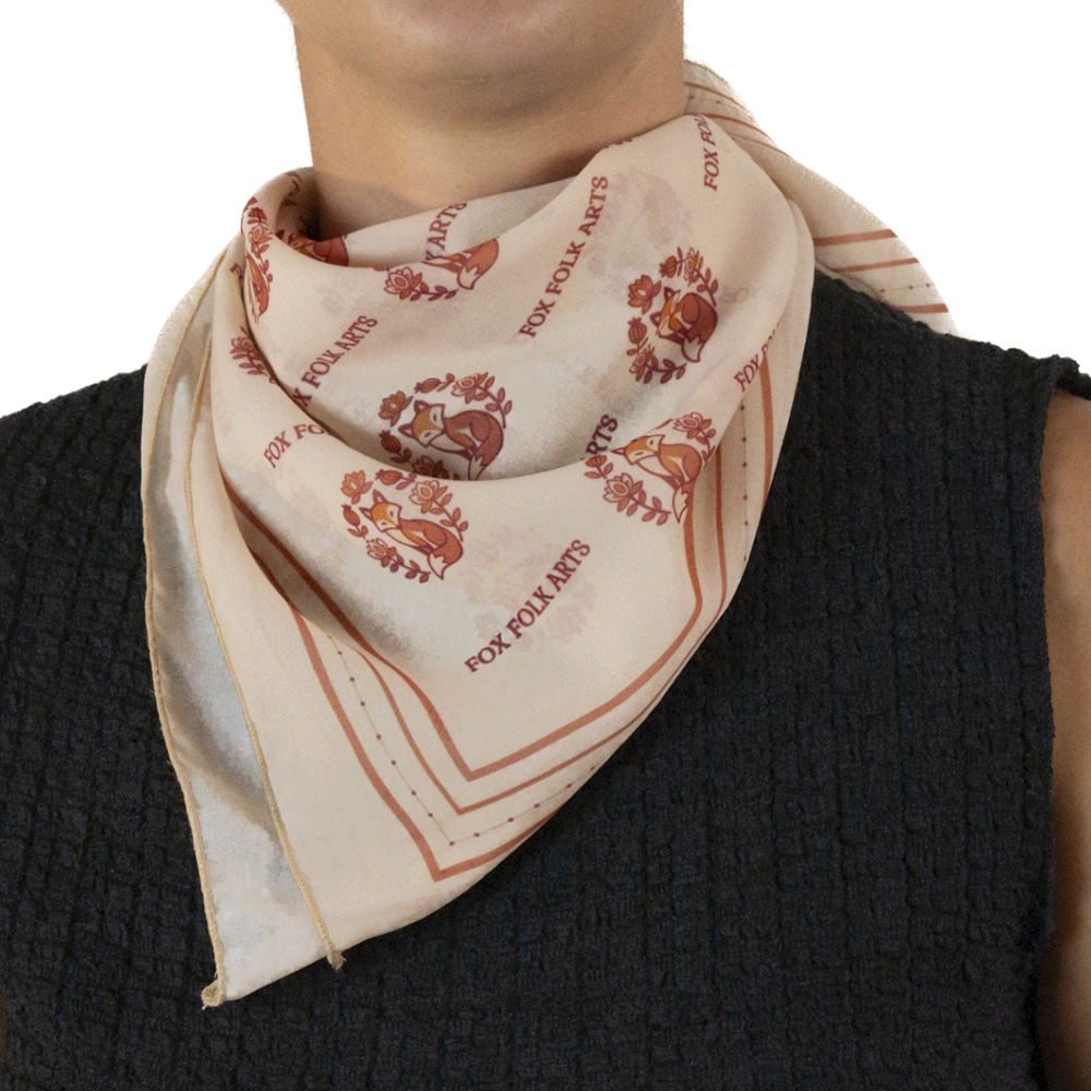 A close-up of a person wearing a cream-colored square scarf, styled around the neck.