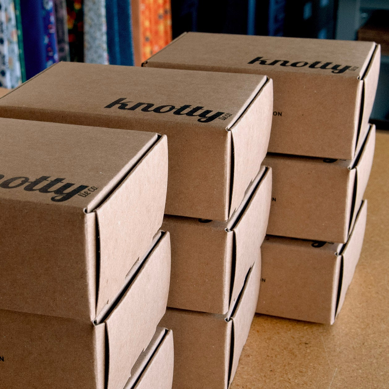 Stack of brown cardboard boxes with 'knotty' branding on a wooden surface.