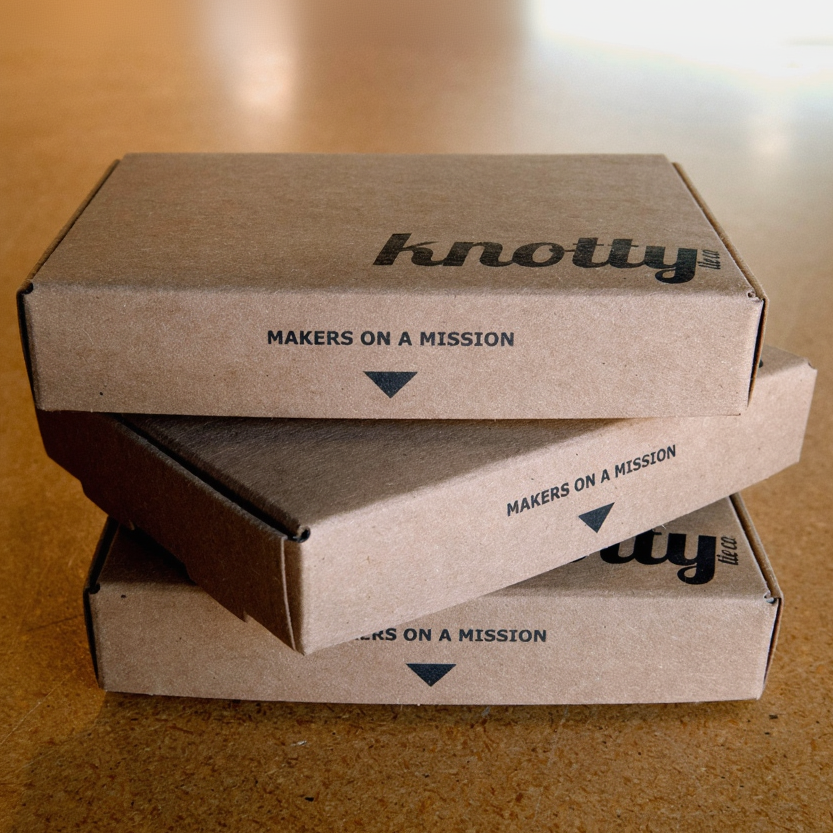 Stack of cardboard boxes with 'knotty' branding on a wooden surface