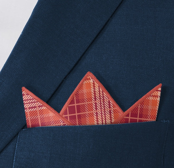 red plaid pocket square folded into a three point fold inside the pocket of a blue suit jacket