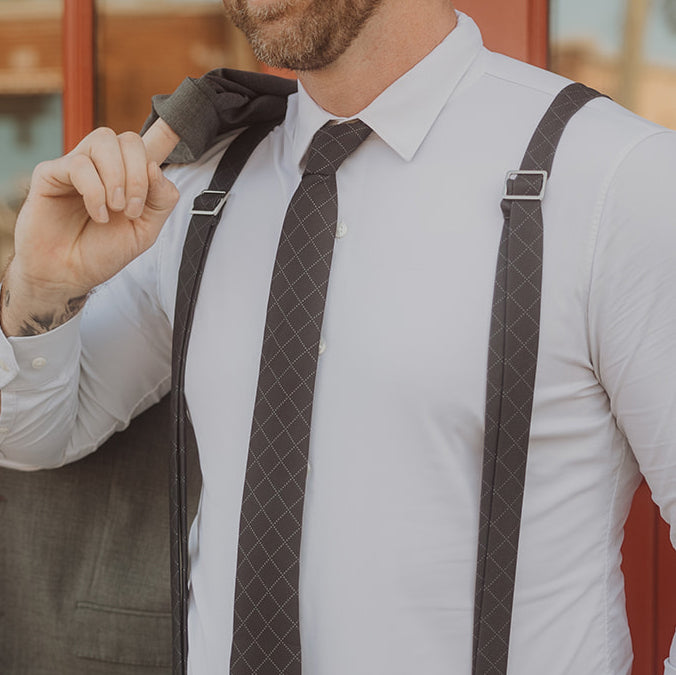 man wearing white shirt and gray suspenders and necktie