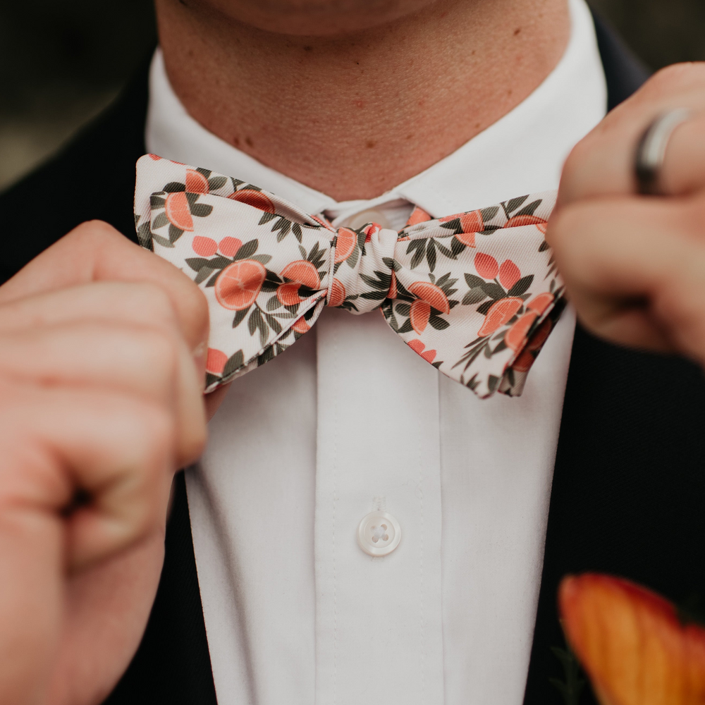 Citrus floral patterned bow tie being pulled tight