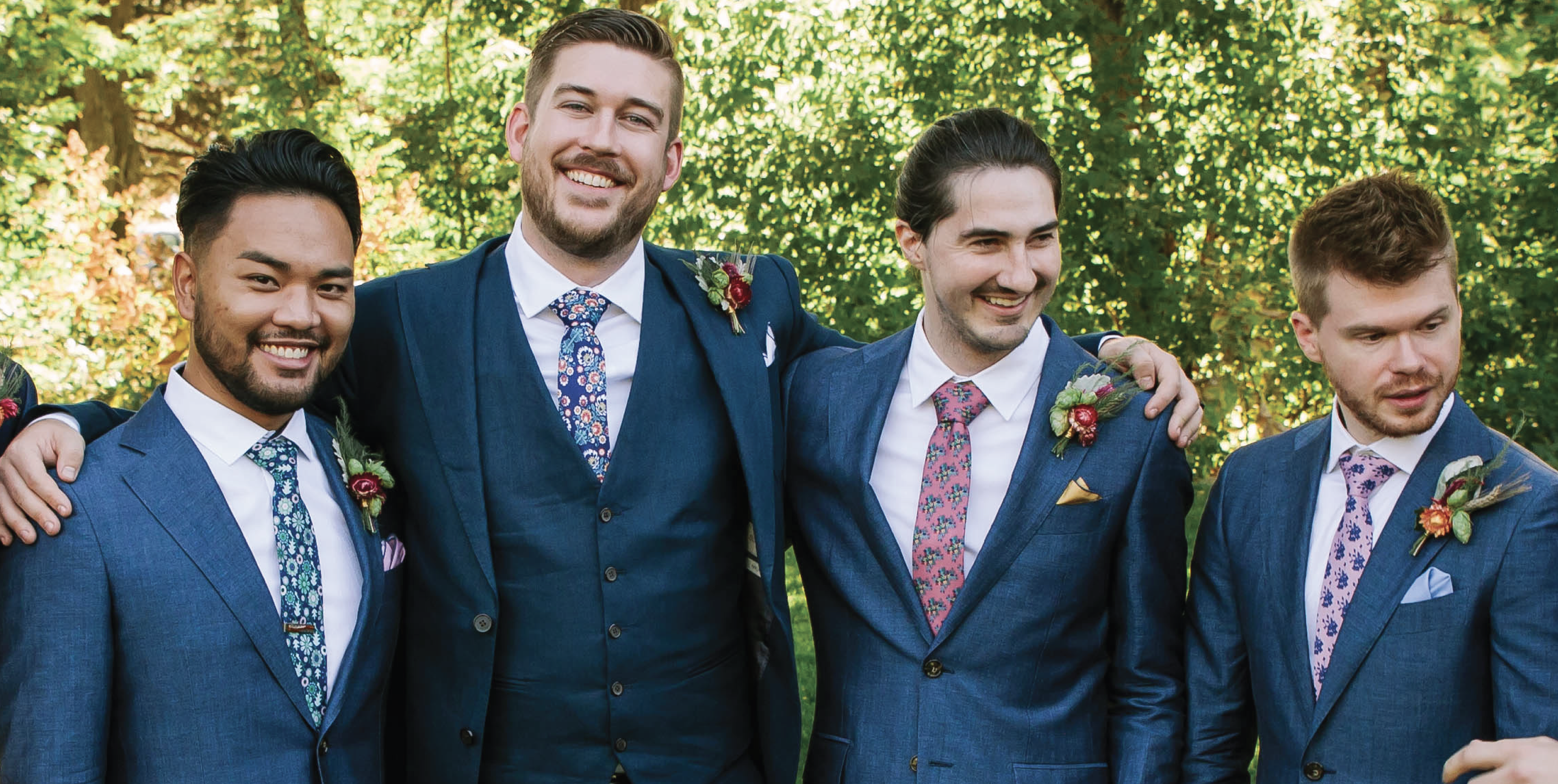 four men wearing mixed floral neckties paired with solid pocket squares