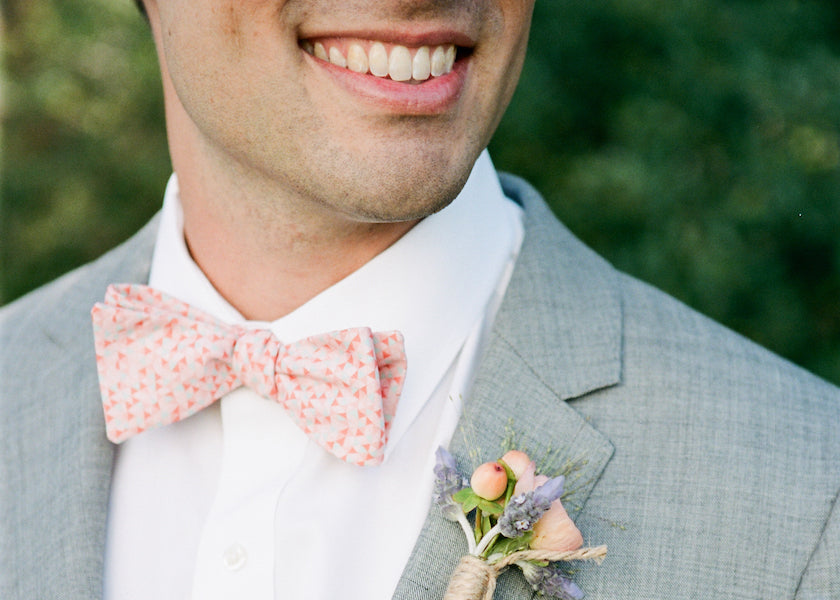 Man smiling wearing custom floral wedding bow tie and grey suit