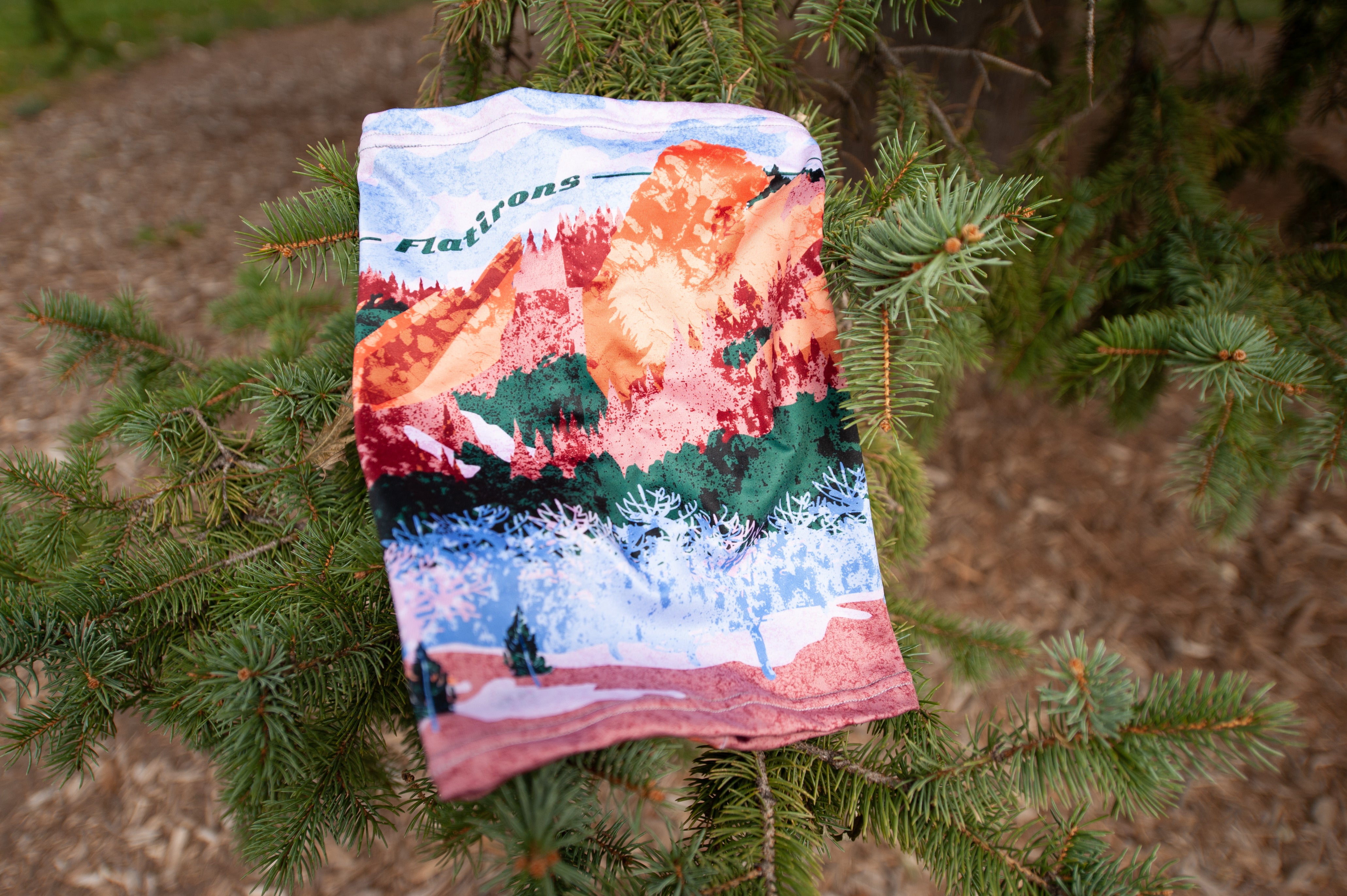 Park inspired neck gaiter hanging on a tree branch