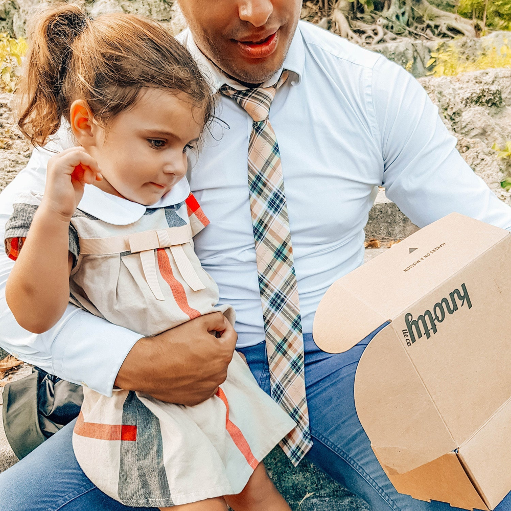 Man wearing a necktie holding a child outdoors.