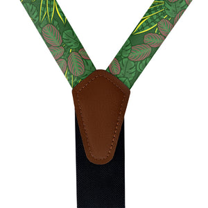 Green leaf-patterned suspenders with a brown leather clip on a white background