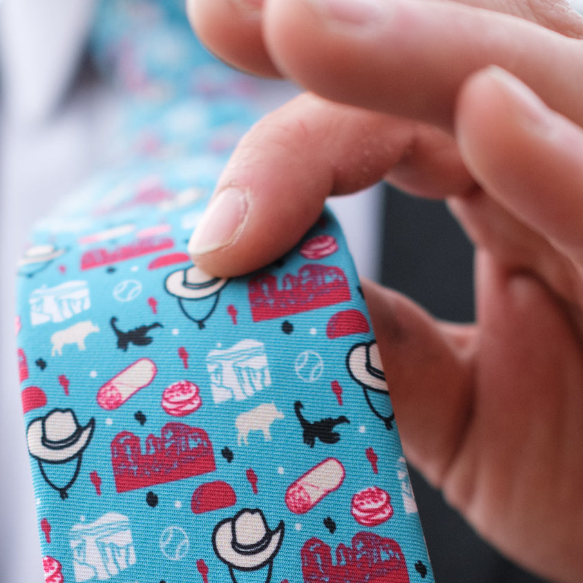 man holding a Texas themed necktie between his fingers