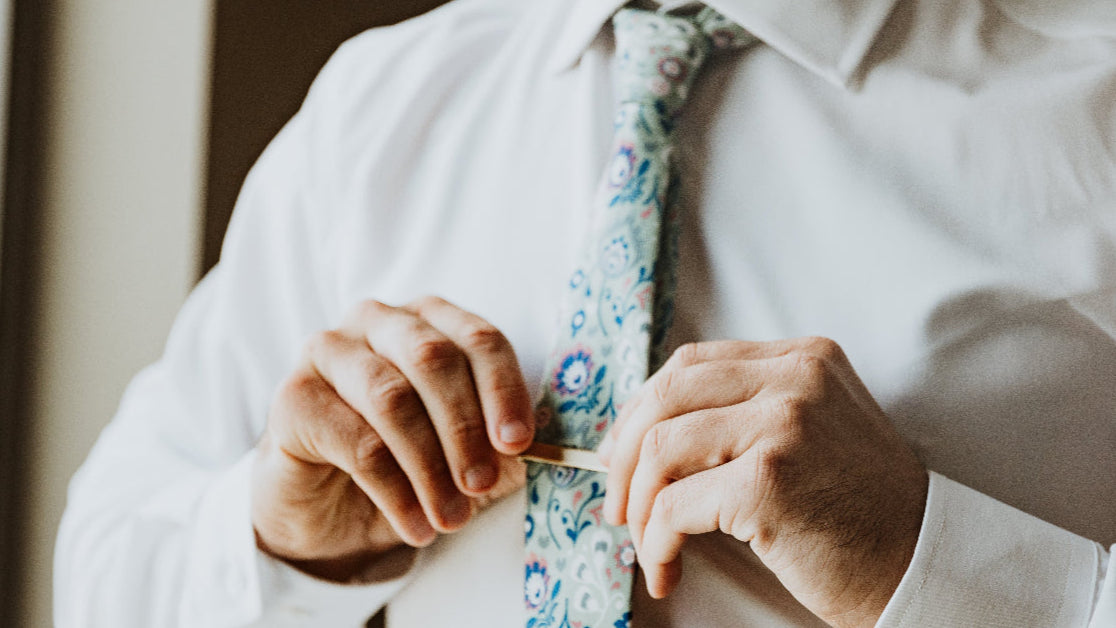 Putting a tie clip on a customized floral necktie