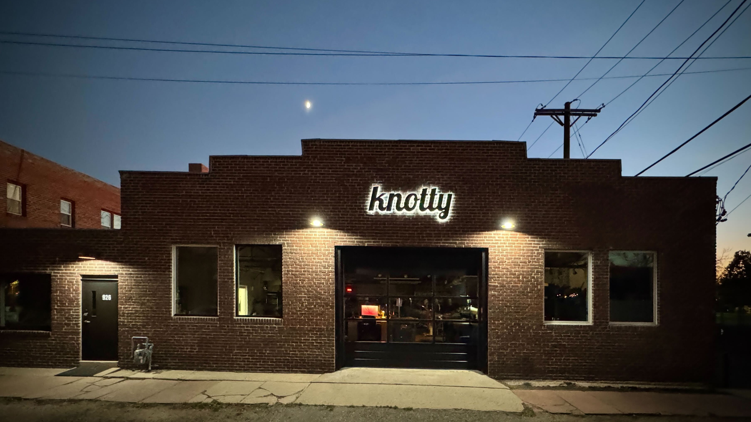 Brick building with 'knotty' sign at night