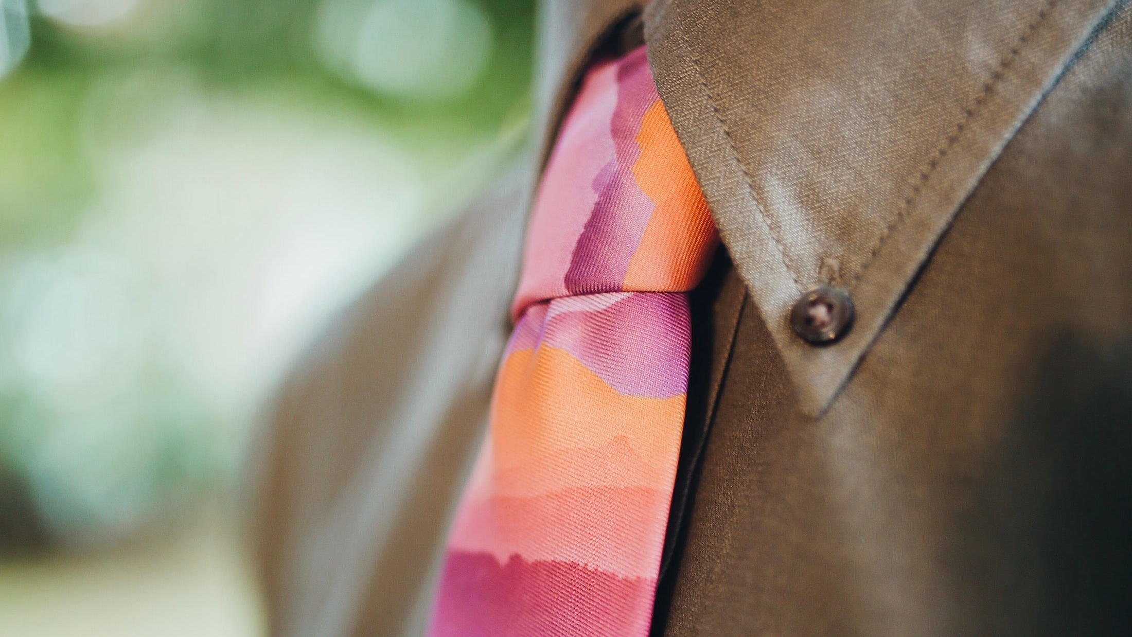 Close-up of man wearing green shirt and colorful sunset print necktie