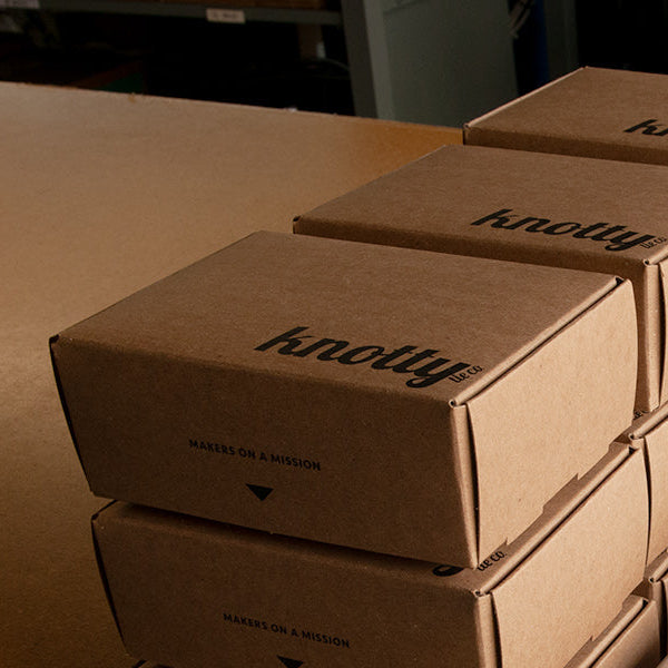 Stack of cardboard boxes with 'Knotty' branding on a table.