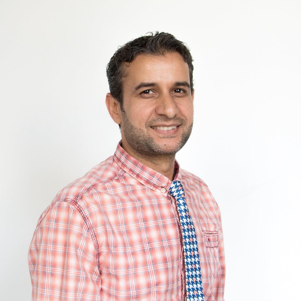 Man wearing a red checkered shirt with a blue tie against a white background