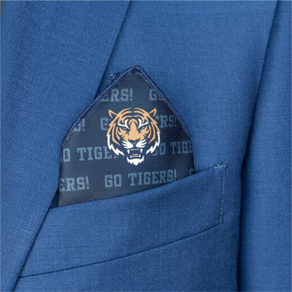 A close-up of a blue suit jacket pocket with a folded pocket square featuring a tiger head logo.
