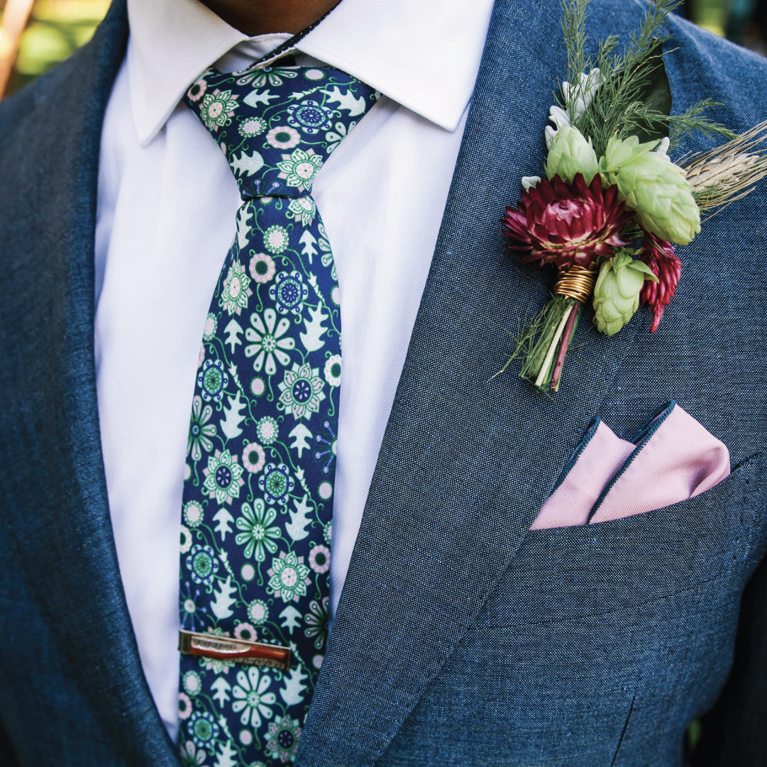 floral necktie and pink pocket square with navy suit and flowers