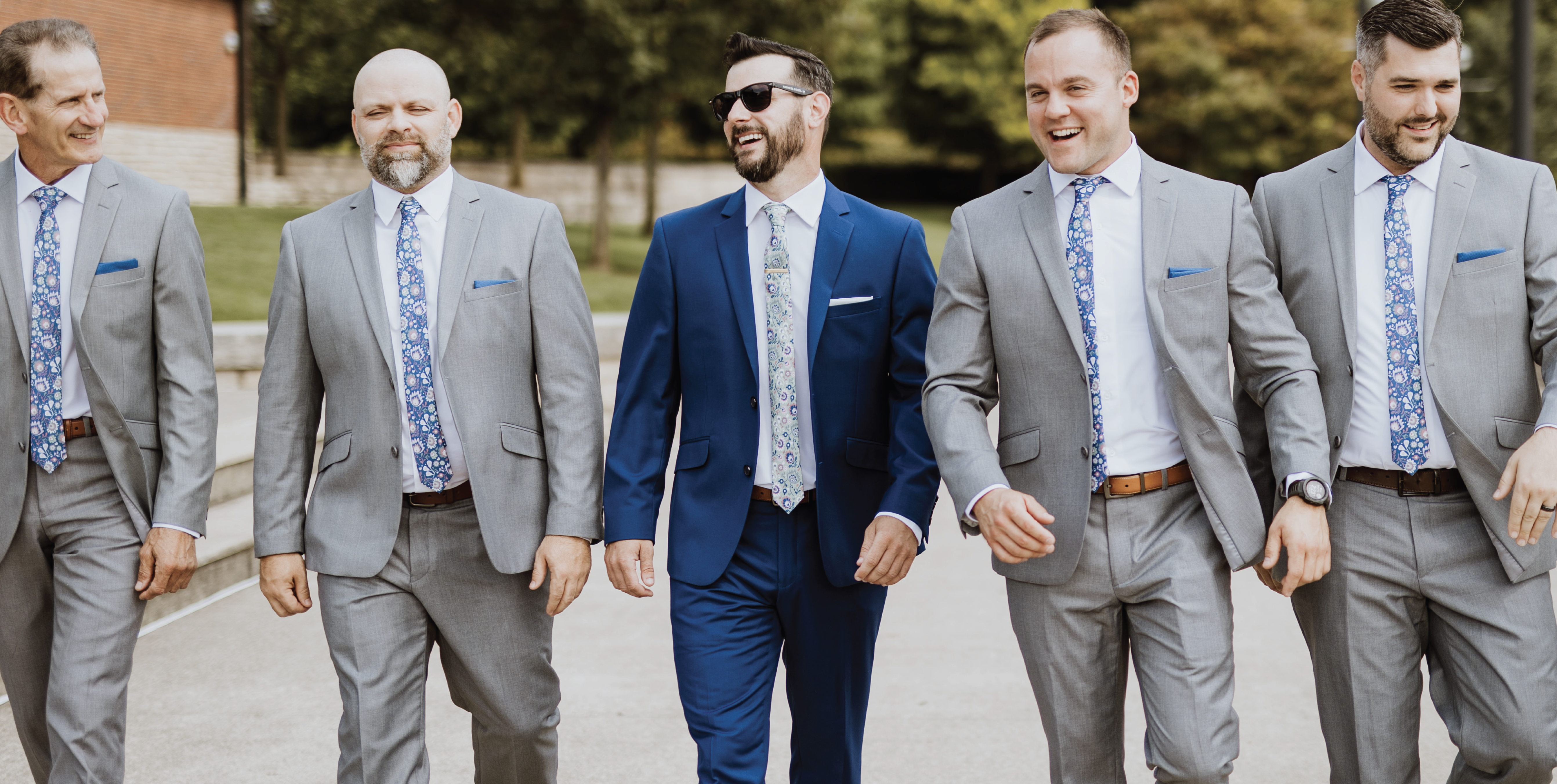 five men walking down street towards camera wearing suits and ties and pocket squares