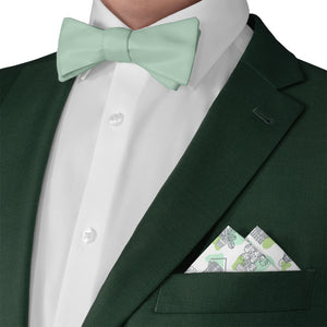 Green suit with mint green bow tie and potted plant patterned pocket square on a white background