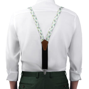 Person wearing a white shirt with floral-patterned suspenders and green pants on a white background