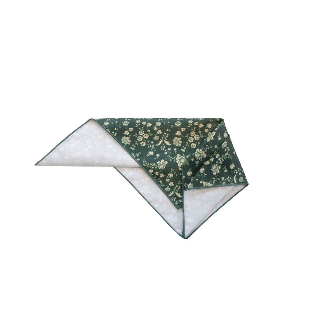 A folded pocket square with a dark green floral print on one side.