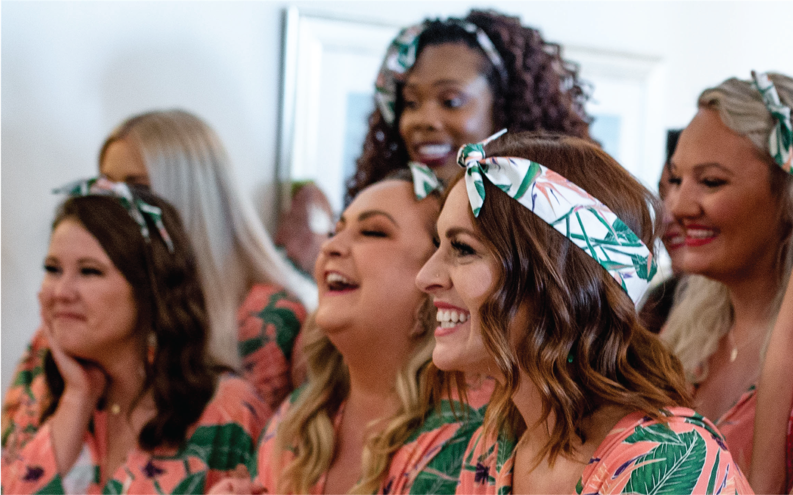women at a bachelorette party wearing matching robes and wedding scarves