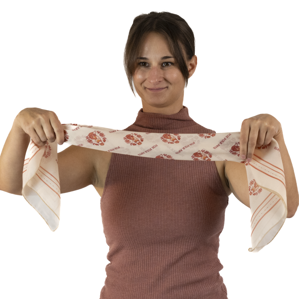 A woman holds up a neatly rolled cream square scarf 