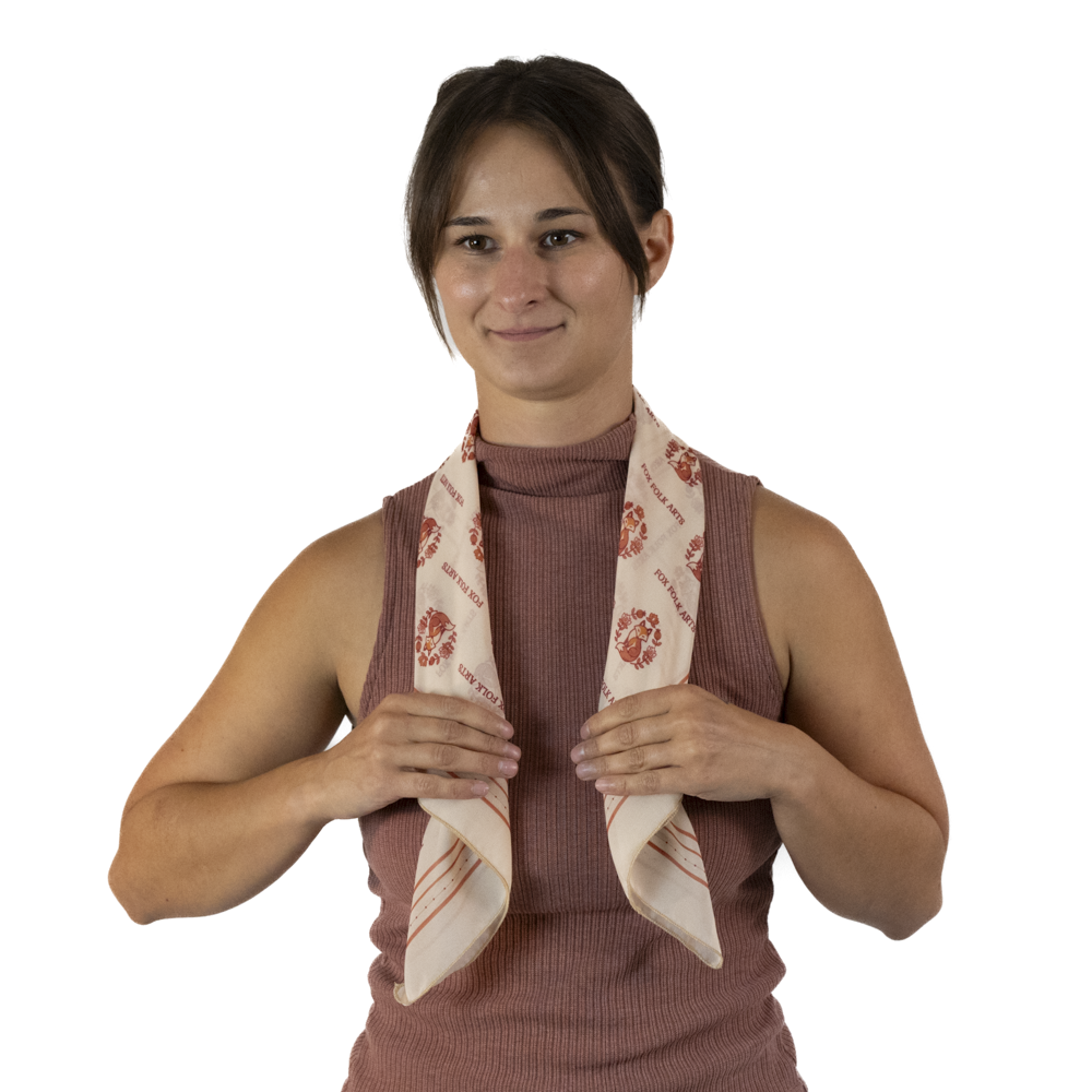A woman draping a rolled cream square scarf around her neck
