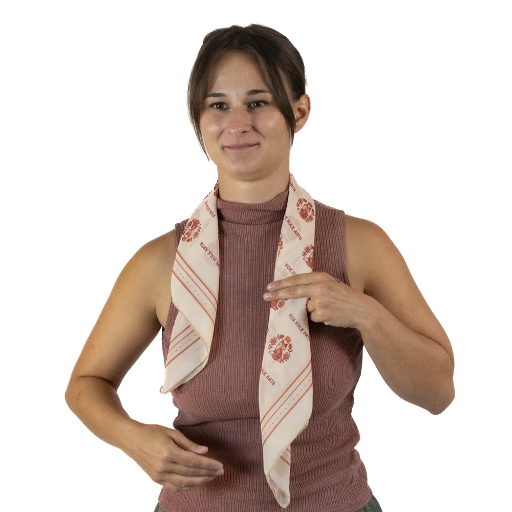 A woman with a rolled cream square scarf around her neck, positioned to be longer on one side