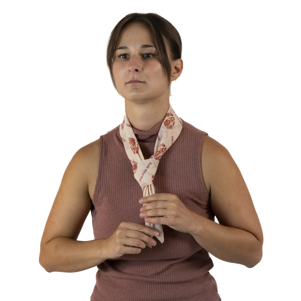 A woman adjusting a tied cream scarf around her neck