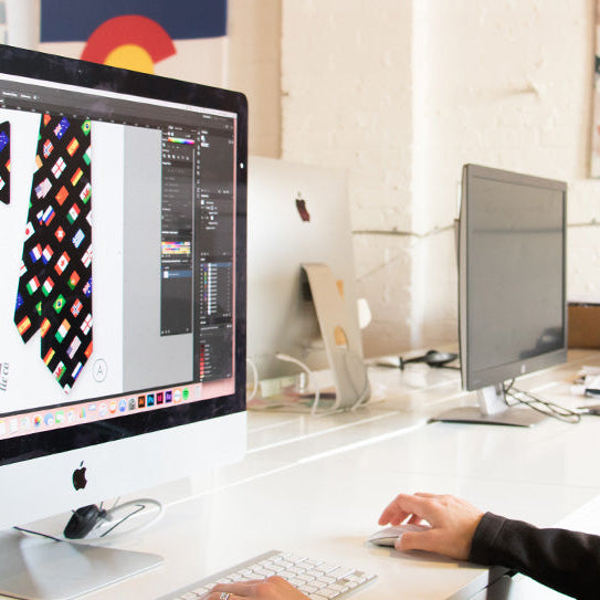 Person using a computer with a colorful bow tie design on the screen in an office setting.