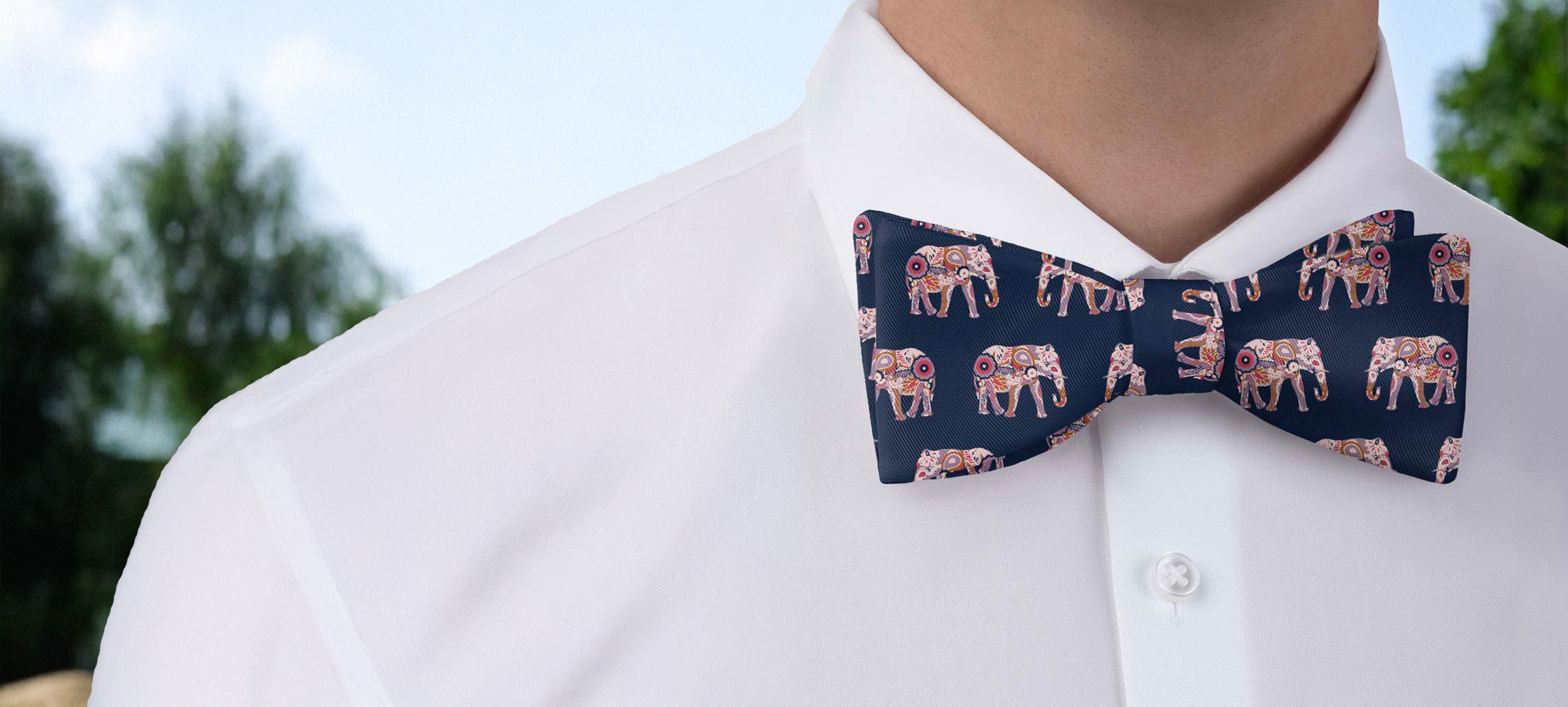 Navy blue bow tie with elephant pattern worn by a person in a white shirt.