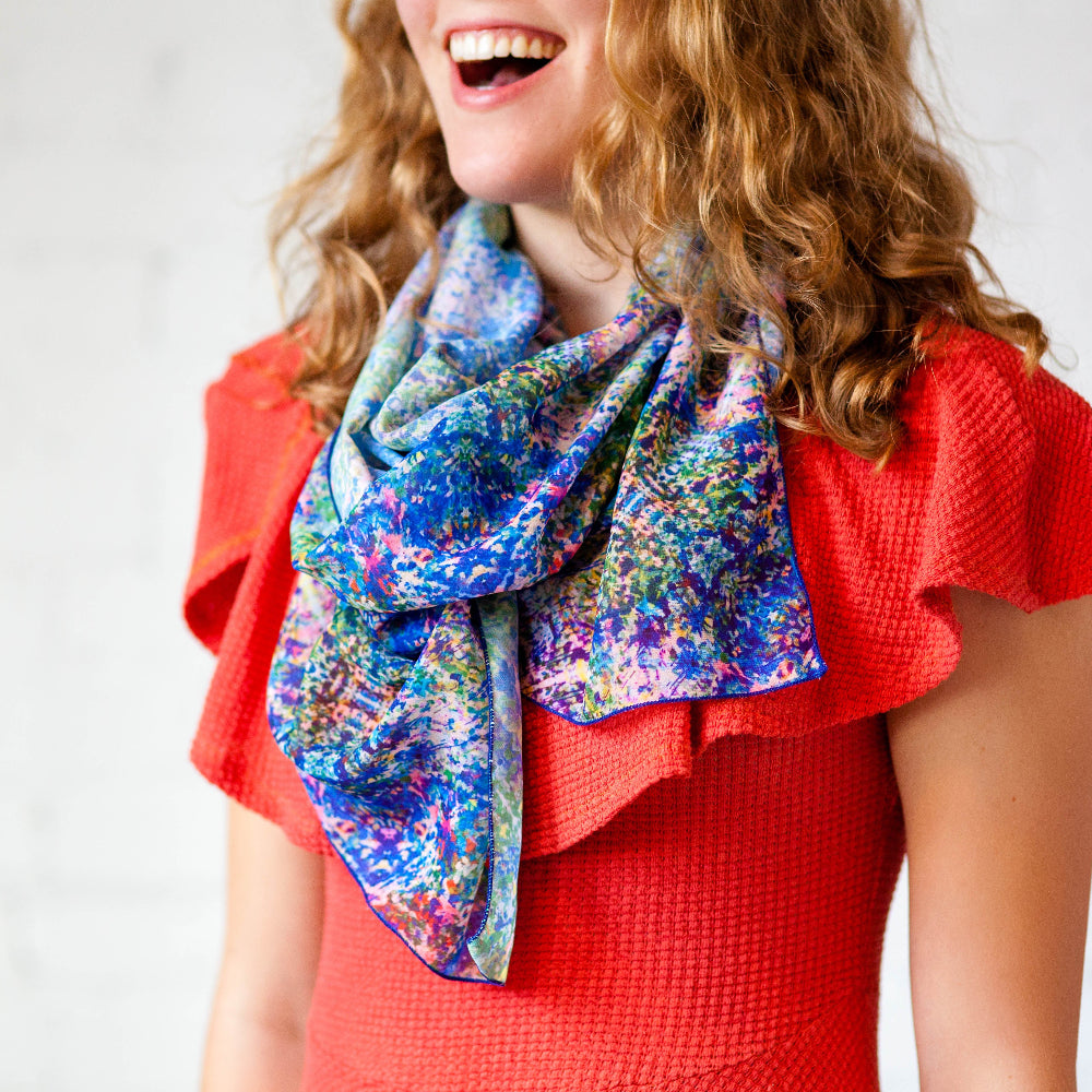 Woman wearing a colorful scarf and red top against a plain background