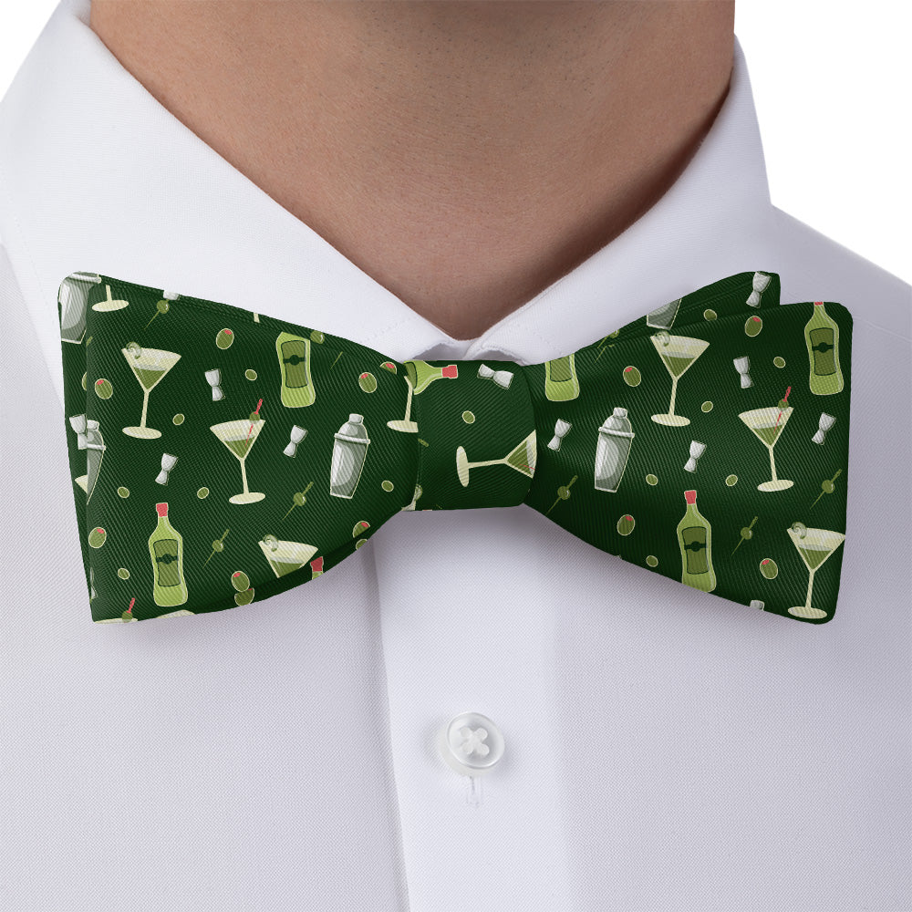 Green bow tie with cocktail pattern worn by a person in a white shirt.