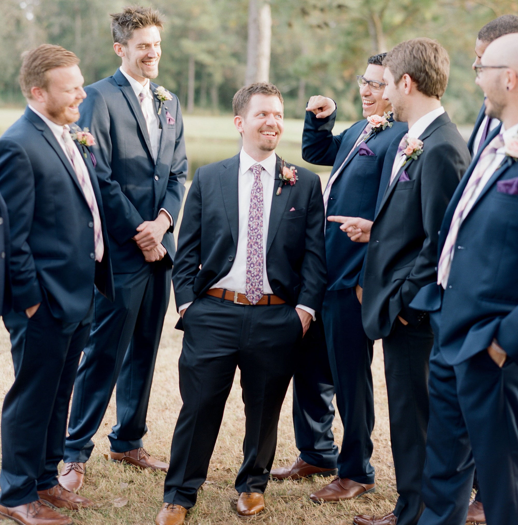 Groom surrounded by groomsmen in outdoor setting