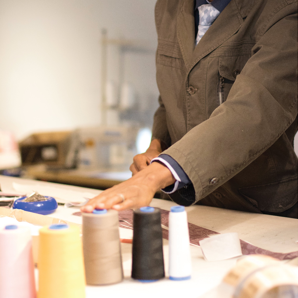Person working with sewing threads and equipment on a table.