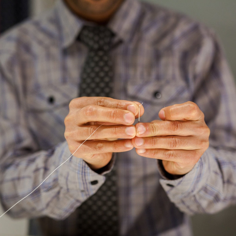 Person holding a thin string or thread with blurred background