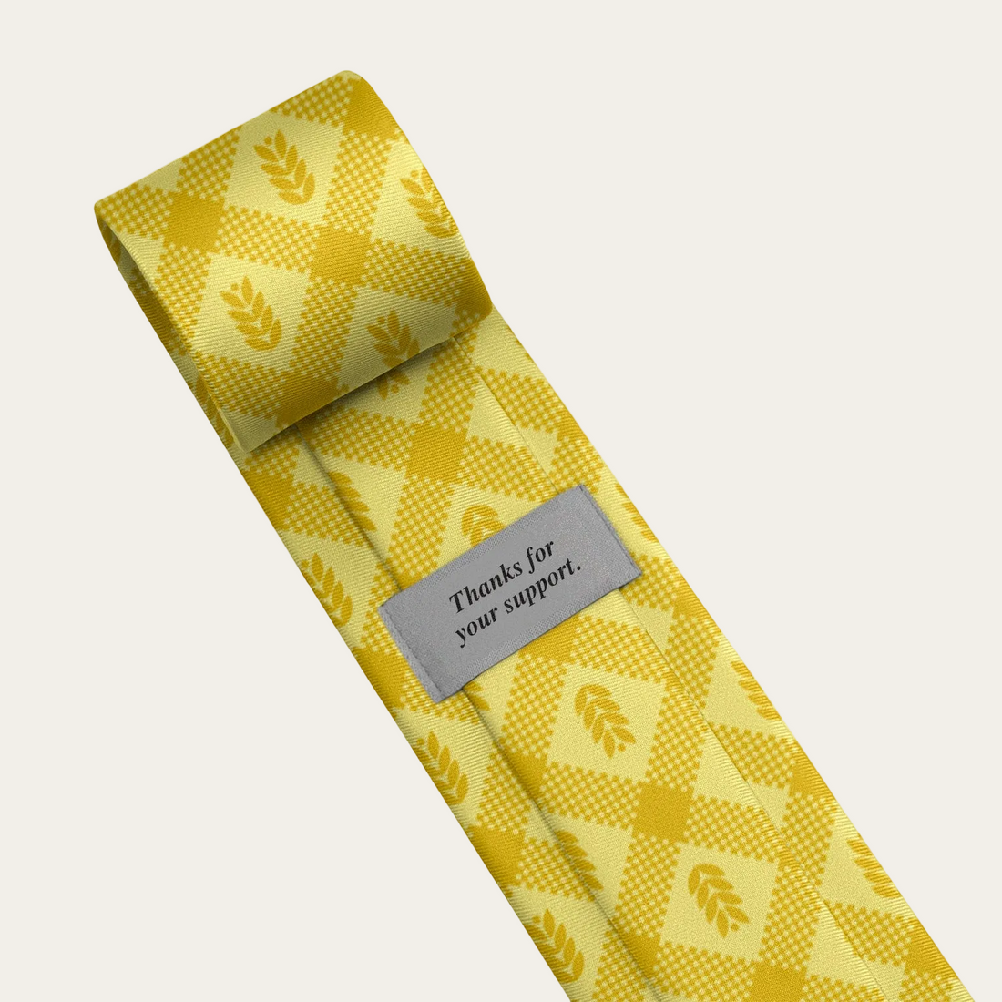 Yellow patterned tie with a label saying "thanks for your support" on a light gray background