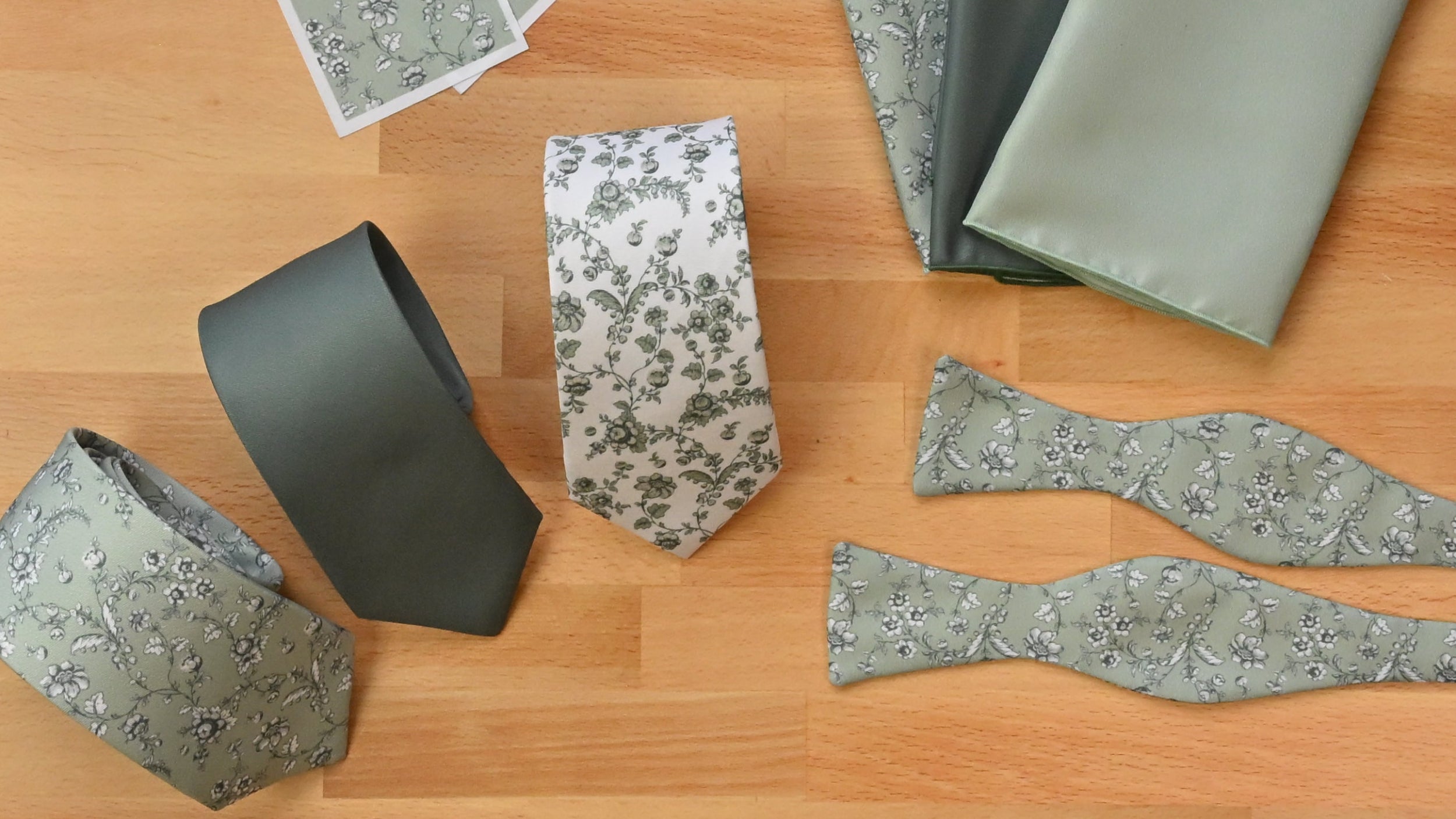 A top-down view of a wooden board displaying various patterned ties, bow ties and pocket squares.